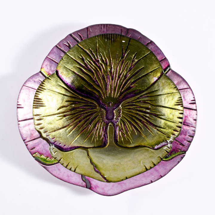 Pansy plate collection featuring a floral-inspired glass design with intricate petal detailing. Available in green canape/bread and butter plate (6.5") and purple salad plate (8.5"), both with iridescent finishes that add a touch of elegance to any tablescape.
