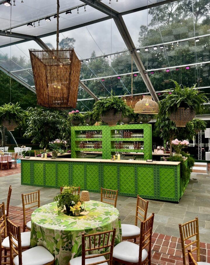 Treillage Bar in vibrant green with a lattice-patterned front and wood countertop, shown in an outdoor garden event setting. The bar can be customized by combining multiple pieces for different lengths. Available in 2', 4', 5', and 6' sections, each 25" wide and 42" high — ideal for creating large or modular bar setups.