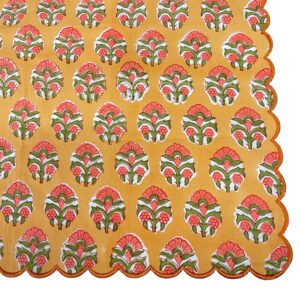 Scalloped dinner napkin in orange and green with a hand-block floral pattern and decorative scalloped edge.