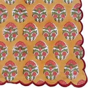 Scalloped tea napkin in orange and green with a small-scale floral block print and decorative scalloped edge.