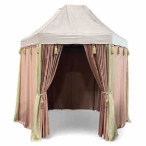 Hexagonal blush and rose velvet event canopy with gold tassel accents, measuring 9' x 6' x 10' high. Features draped velvet panels, tied-back openings, and a soft blush top cover, ideal for lounge areas, photos, or VIP spaces.