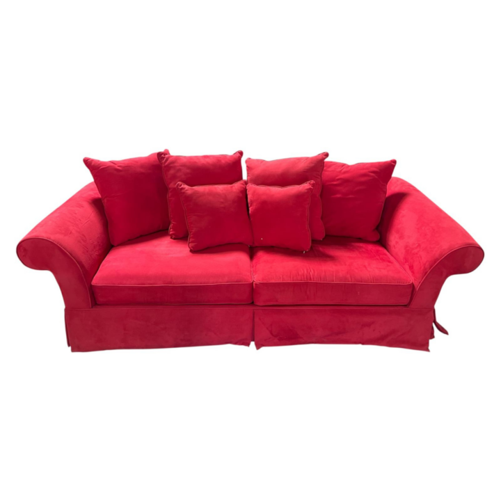 luxurious red velvet sofa with rolled arms, plush seat cushions, and matching accent pillows in a bold ruby red upholstery.